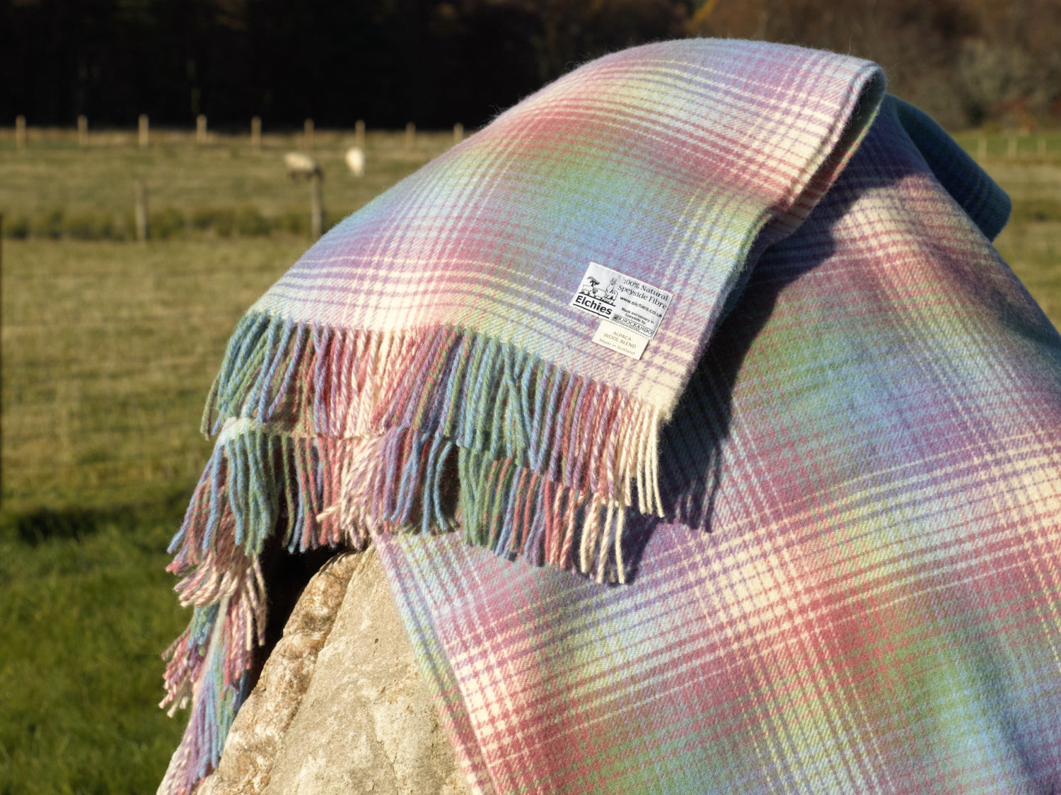 A colourful woollen blanket displayed over a rock in the sun.