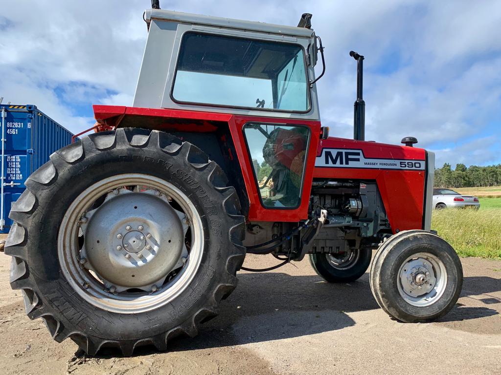 Red and gray tractor with 'MF' branding on a rural background.